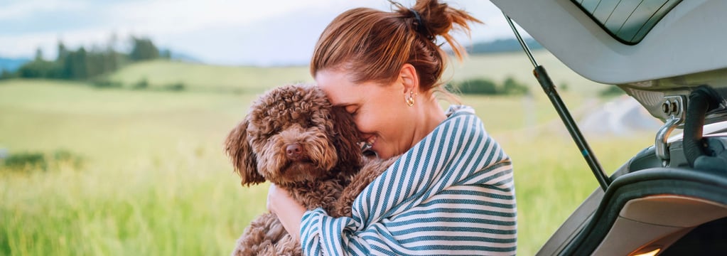 A woman in a striped blanket hugging her Maltipoo.