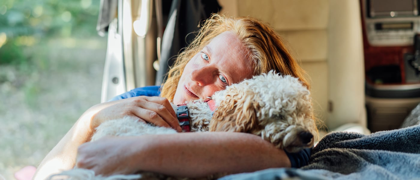 A dog owner cuddling their Cockapoo.