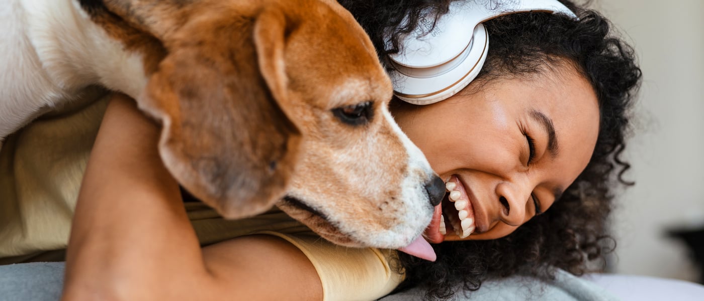 A woman laughing and holding her beagle.