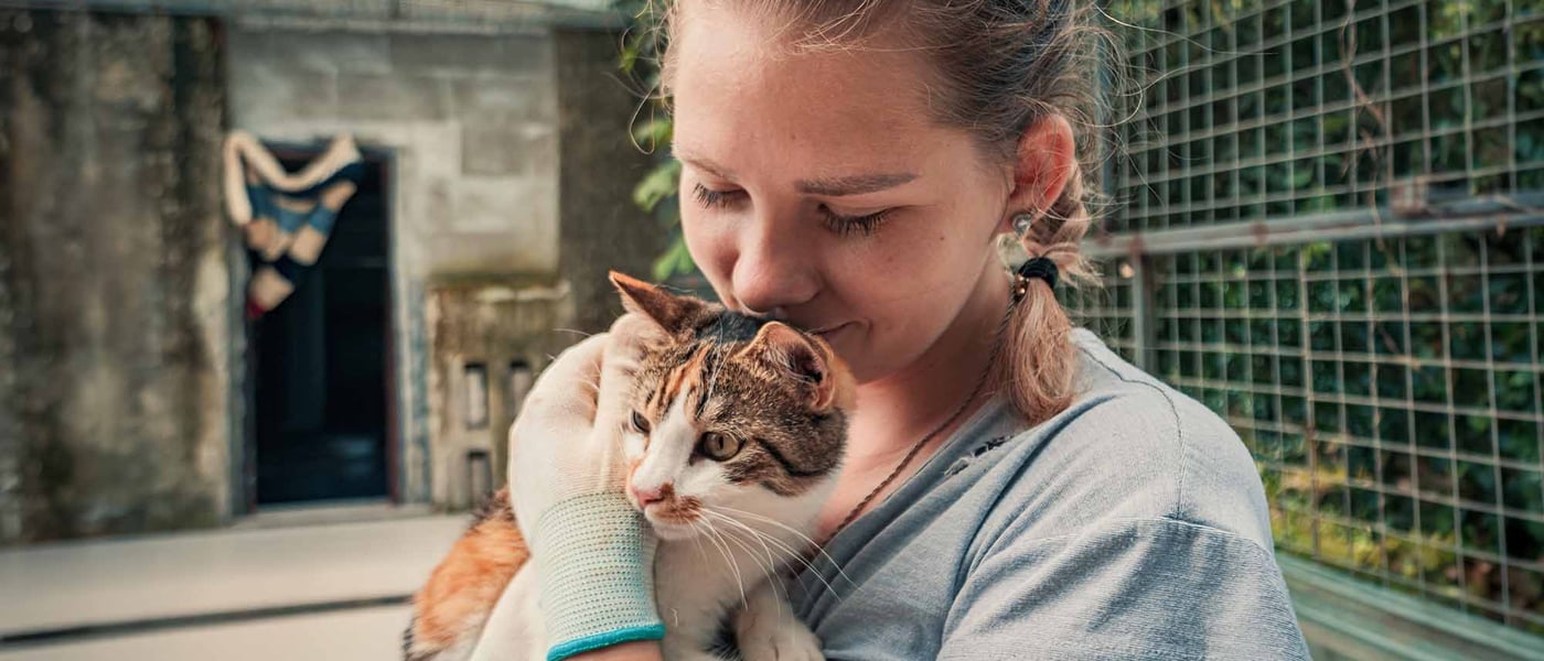 A woman in gloves holding a cat