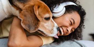 A woman laughing and holding her beagle.