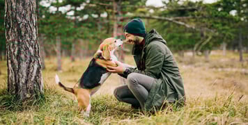A man crouching down to his beagle.