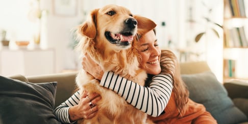 A woman in a striped shirt hugging a dog.