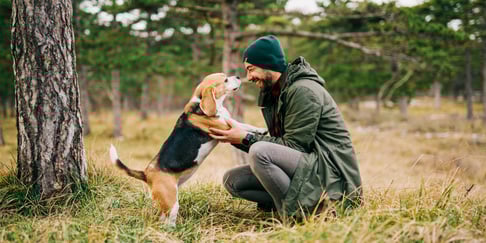 A man crouching down to his beagle.