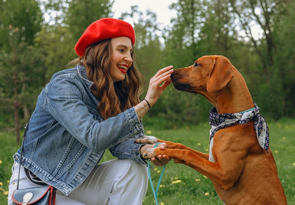 A woman in a red beret giving her dog a treat.