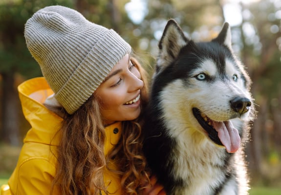 A woman in a yellow jacket with her Siberian Husky.