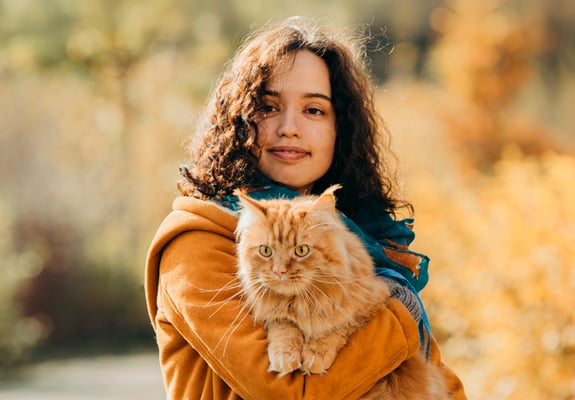 A woman in an orange coat holding an orange cat.