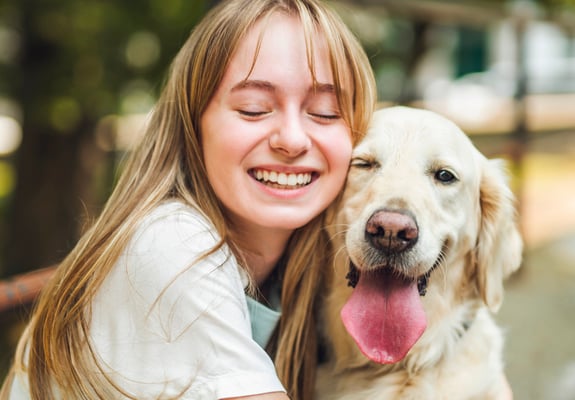 Owner smiling next to Golden Retriever dog with it's tongue out