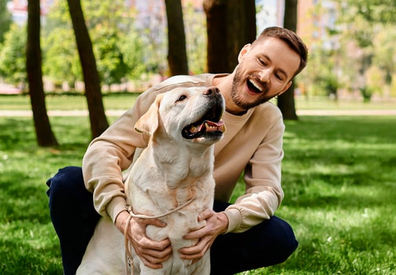 A man hugging his labrador in a park.