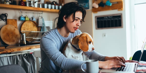 A man sitting at a dining table with a Beagle on his lap.