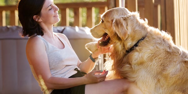 A woman tickling her golden retriever's chin.