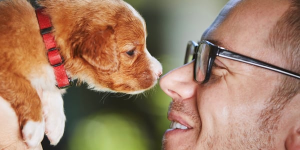 A man nose to nose with a puppy.