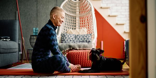 A dog owner sharing a yoga mat with their dog.
