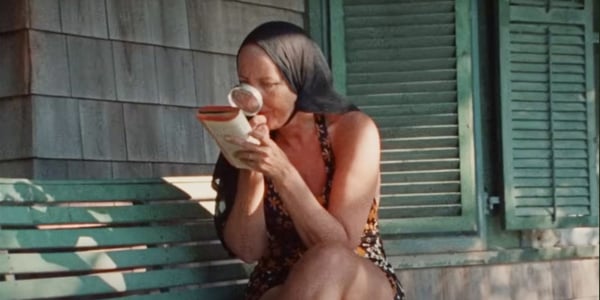 Little Edie sitting on a bench reading horoscopes.