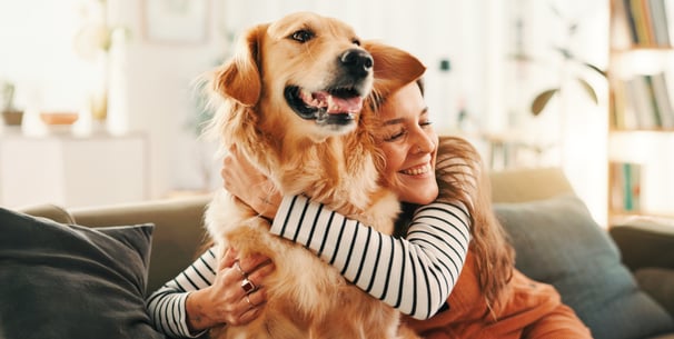 A woman in a striped shirt hugging a dog.