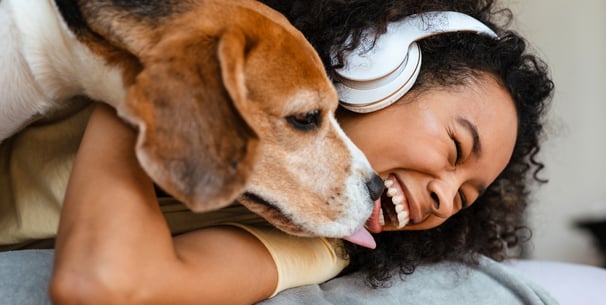 A woman laughing and holding her beagle.