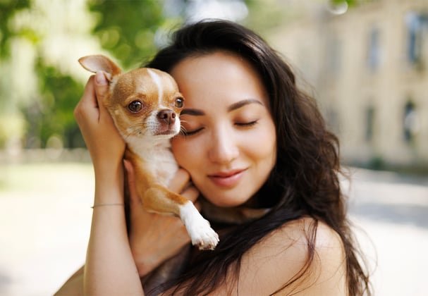 A woman hugging her Chihuahua.