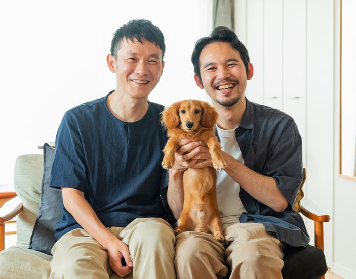 Two men holding their miniature dachshund.