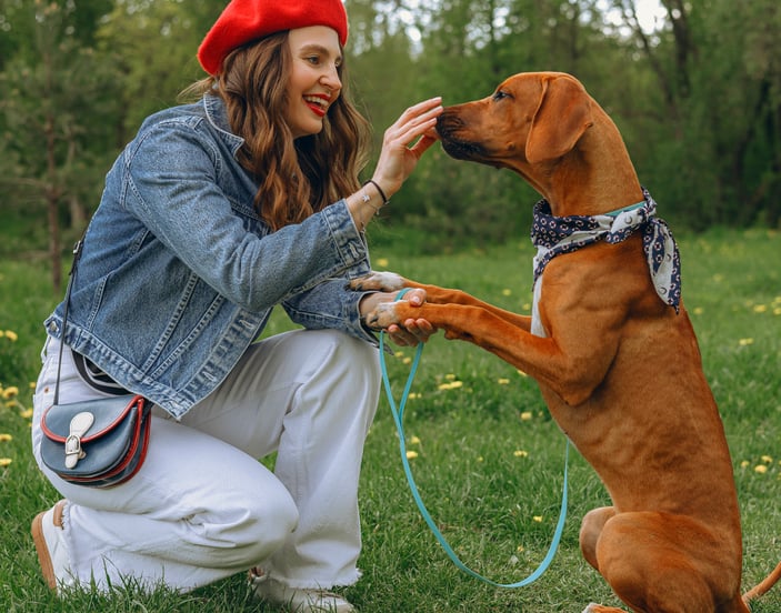 A woman in a red beret giving her dog a treat.