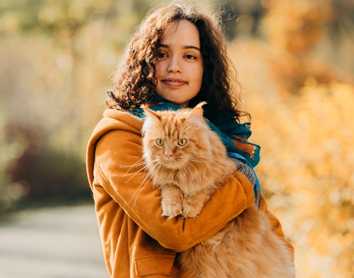 A woman in an orange coat holding an orange cat.
