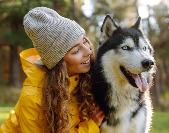 A woman in a yellow jacket with her Siberian Husky.