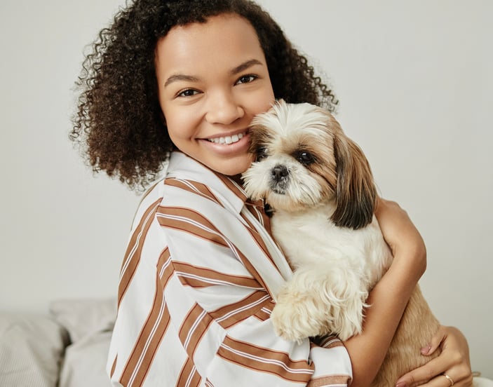 A woman cuddles her Shih Tzu