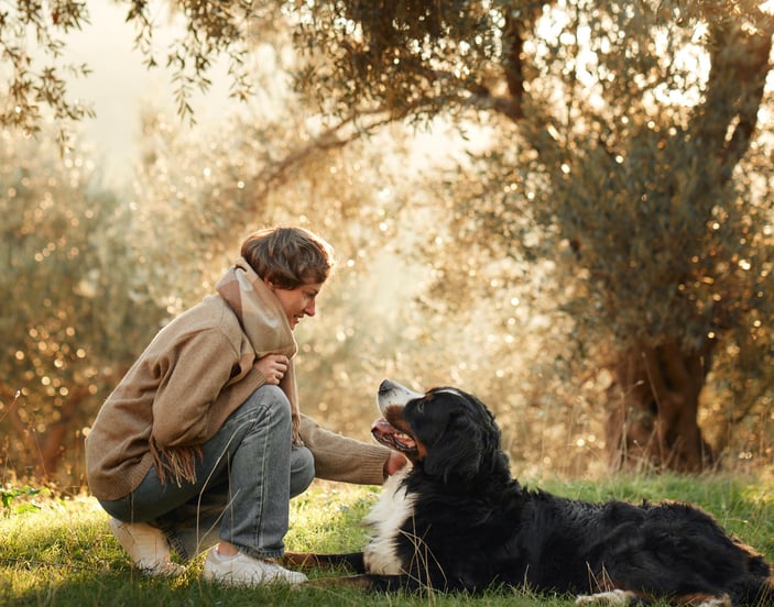 A woman stroking her BMD in the grass.