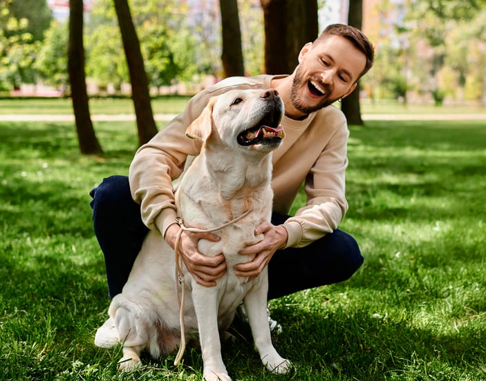 A man hugging his labrador in a park.