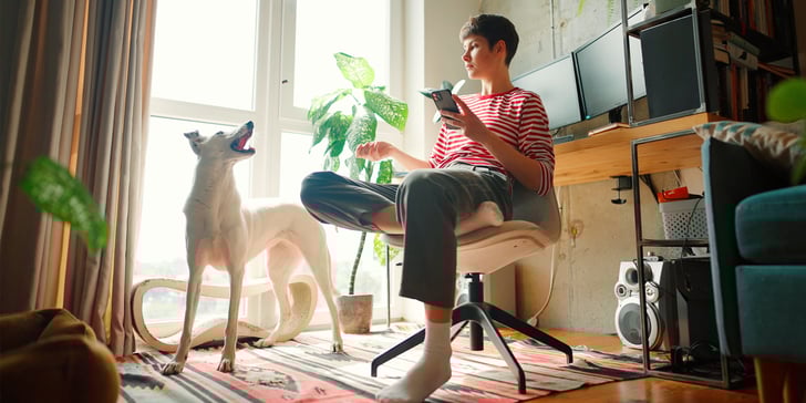A woman in a striped shirt sitting down and talking to her dog.