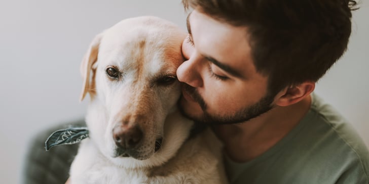 A man snuggling up to his labrador.