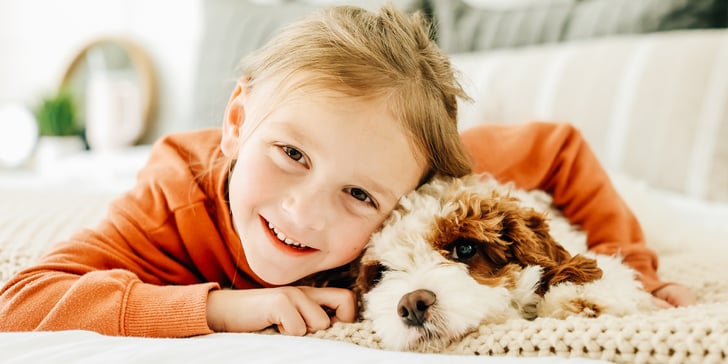 A child and a Cavapoo laying on a couch.