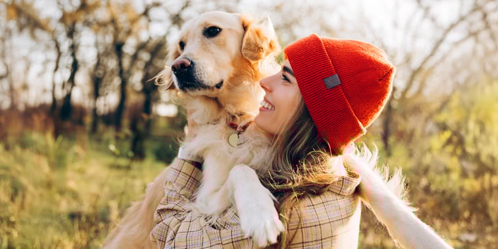 A woman in a red hat hugging a golden retriever.
