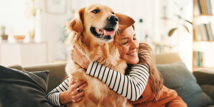 A woman in a striped shirt hugging a dog.