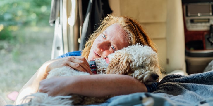A dog owner cuddling their Cockapoo.