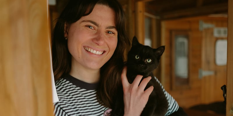 A woman in a striped t-shirt holding a black cat.