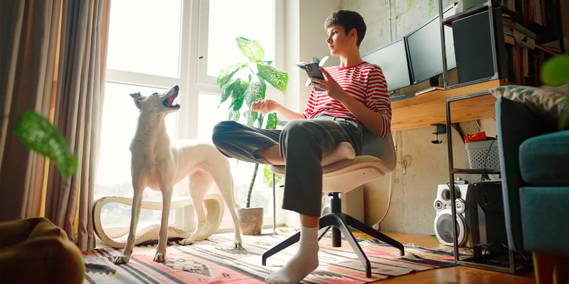 A woman in a striped shirt sitting down and talking to her dog.