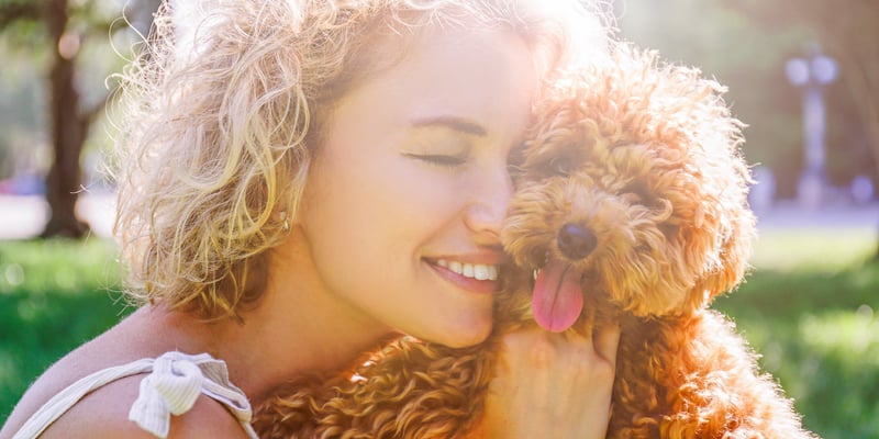 woman cuddling maltipoo outside