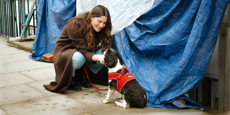 a woman crouching down and petting her dog