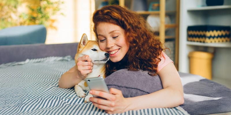 A smiling woman sat with her Shiba Inu.