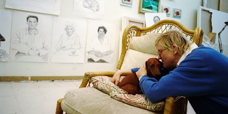 David Hockney kissing his dachshund. 