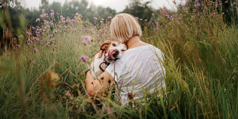A woman hugging her dog in a field.