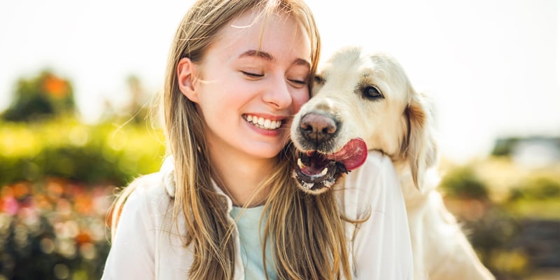 A girl smiling next to her golden retriever.