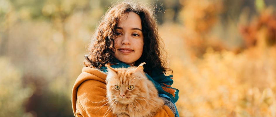A woman in an orange coat holding an orange cat.
