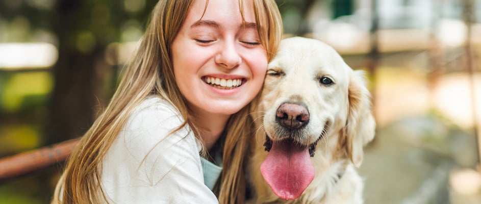 Owner smiling next to Golden Retriever dog with it's tongue out