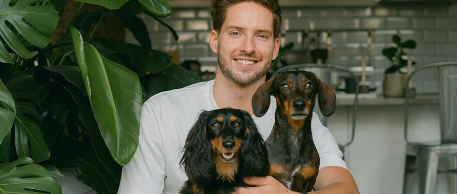 A man protected by pet insurance sat with his dachshund dogs. 