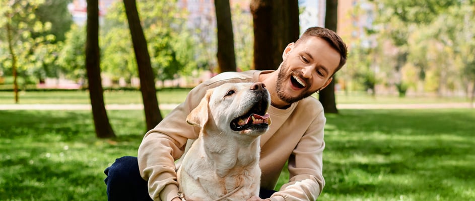 A man hugging his labrador in a park.