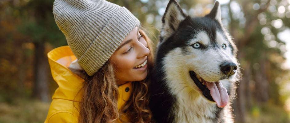 A woman in a yellow jacket with her Siberian Husky.