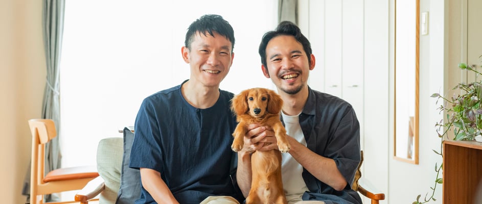 Two men holding their miniature dachshund.