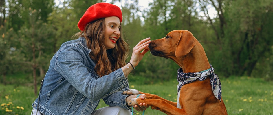 A woman in a red beret giving her dog a treat.